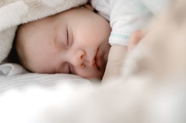Top 5 Best Baby Monitors of 2019, a sleeping baby covered in a white blanket.